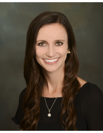 Lindsay Brown, MD posing for her headshot, wearing a black dress, and a thin necklace with a pearl, received the DAPM Teacher of the Year award.