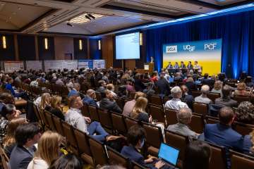 Audience at a conference listening to a panel discussion on stage.