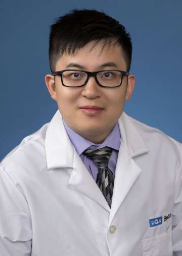 Head shot of Yuxing Xia in white lab coat, looking at camera
