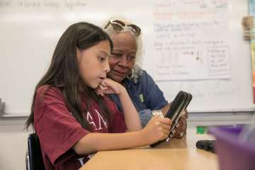 An older woman working with a young student