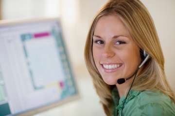 Woman sitting at computer smiling, wearing headset