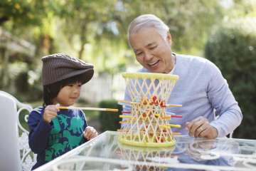 Child playing game outside with grandfather