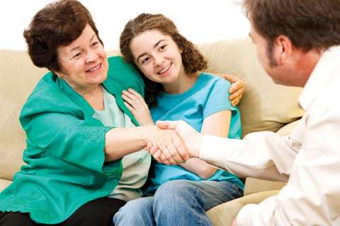 Care provider shaking hands with a woman and child in her arms