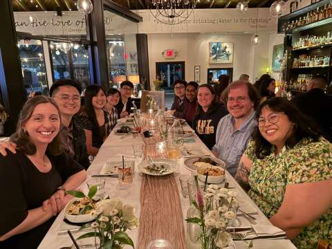 Group of people smiling around a long restaurant dinner table