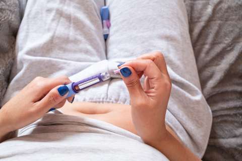 Woman injecting a syringe into her-belly. Medication for the medical treatment of obesity