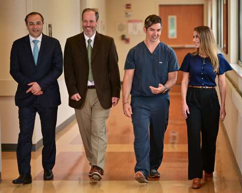 Four medical staff walking together in a hospital hallway
