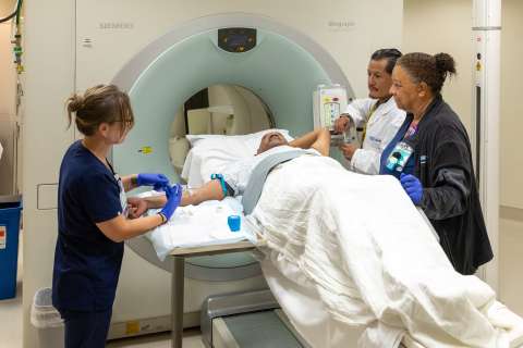 Healthcare professionals assisting a patient during a CT scan procedure.