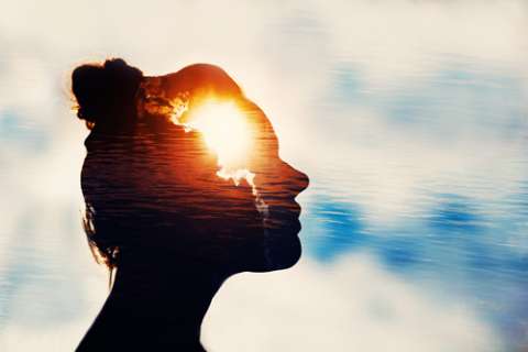 Woman outside with an image of the sun peeking out from behind the clouds placed over her face