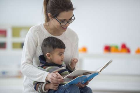 Child sitting in mother's lap reading book