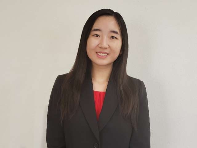 Head-and-shoulders portrait of person in black blazer and red top with face blurred.