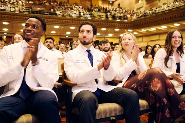 DGSOM medical students applaud in a large lecture hall.