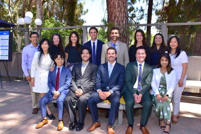 the group of pain fellowship program members dressed in suits and dresses outside near a tree.