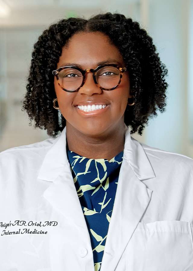 Headshot of Anige'r Oriol, MD in a white Lab Coat
