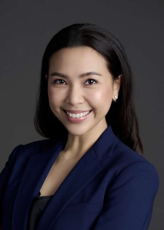 Professional headshot of a person in a navy blazer against a dark background.