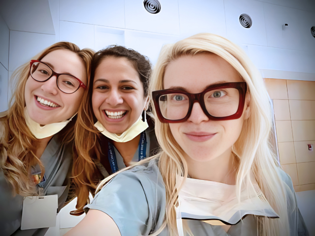 Dr. Christie and two residents taking a selfie wearing gray scrubs.