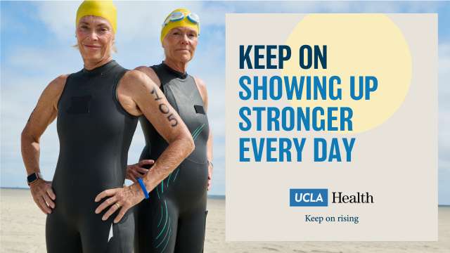 Two female swimmers wearing sleeveless wet suits and rubber swim caps