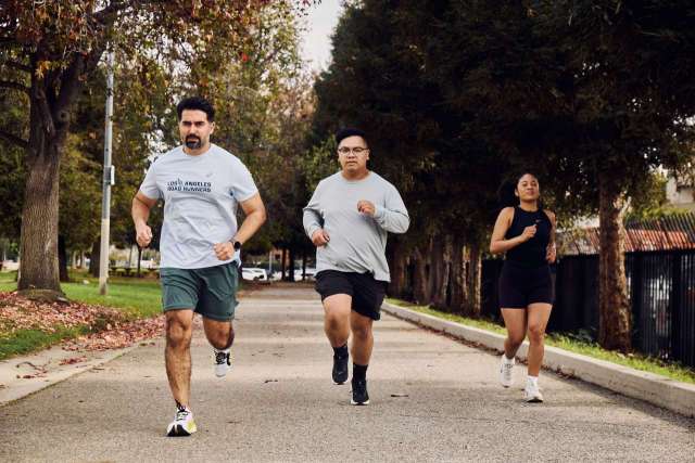 Three people jogging together on a tree-lined path.
