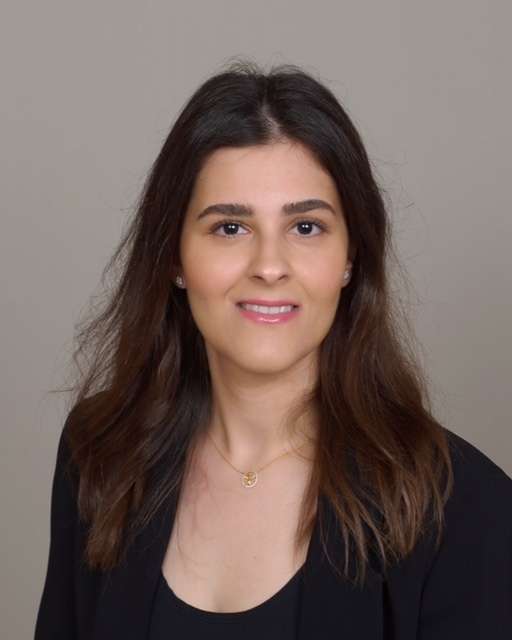 A headshot of Linha Mohammed, a young woman with long dark hair, smiling gently against a plain background.
