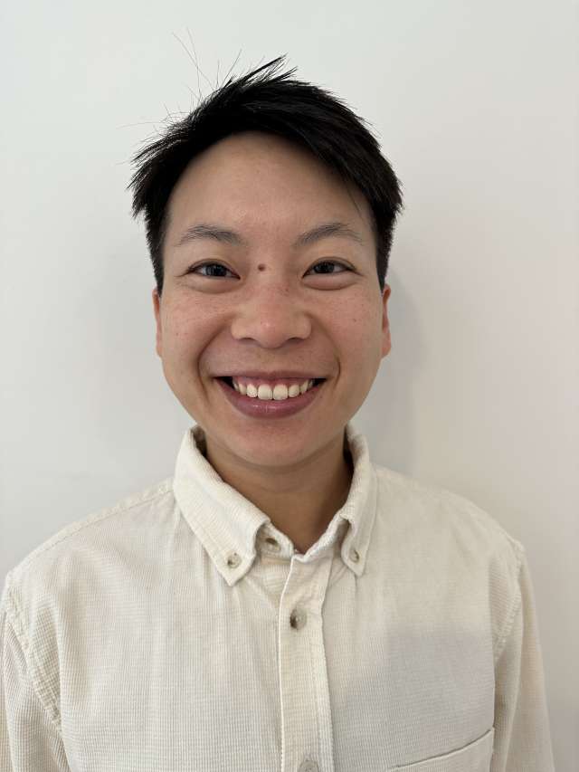 Smiling person in a light collared shirt against a plain white background