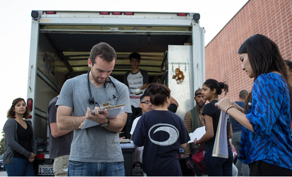 Volunteers assist and gather information from patients outside the UCLA Mobile Clinic truck during a community outreach event.