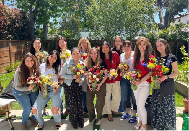 a dozen Internal Medicine Residents and Faculty posing in a backyard with flower bouquets