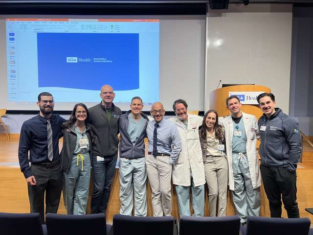 Group of healthcare professionals posing together on a stage during Grand Rounds at UCLA Health.