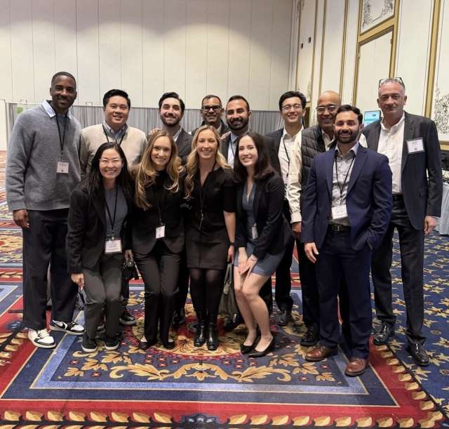 Conference attendees posing together in a hotel ballroom, wearing name badges.
