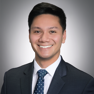 A headshot of Christopher Pardo, a smiling man with short dark hair, wearing a dark suit and a blue patterned tie.