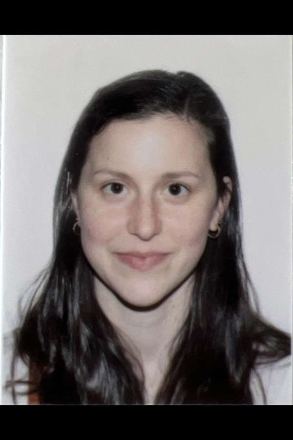 Woman with long dark hair facing camera against plain white background.