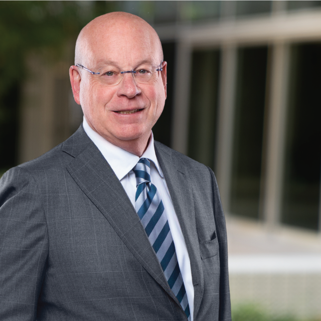 Dr. Michael Steinberg, wearing glasses and a dark gray suit with a striped tie, smiling in a professional headshot.