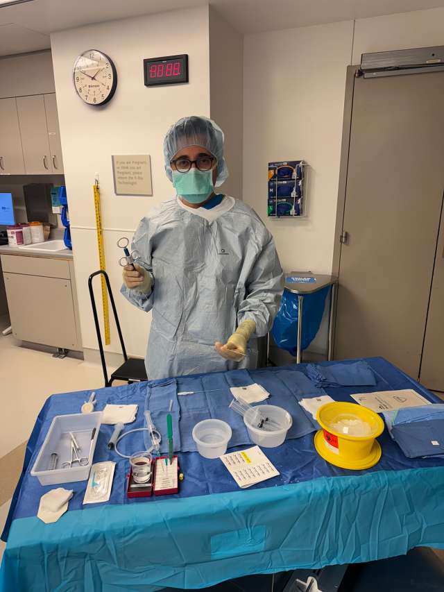 Healthcare professional in scrubs stands by a table with medical supplies.