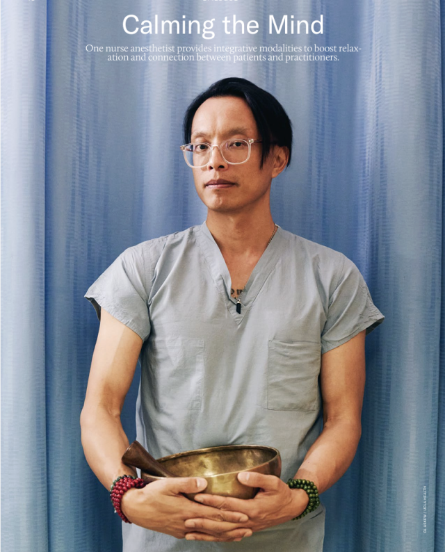 Clinician standing in front of blue curtain holding gold tibetan bowl
