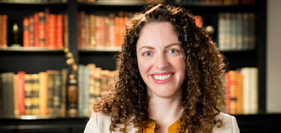 Dr. Catherine Lindsay smiling in front of a full bookshelf