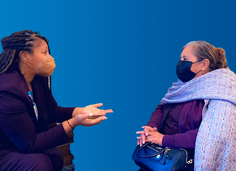 a Patient Advocate speaking with a patient and they both have masks and a blue background.