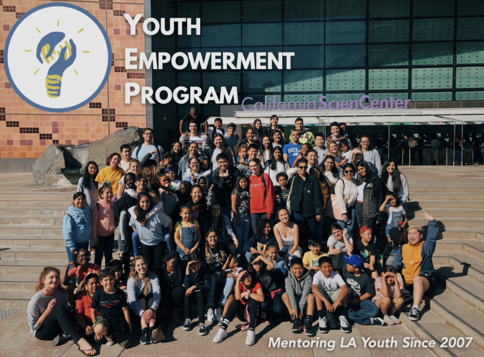 A large group of young people are gathered on steps in front of the California Science building. A banner reads "Youth Empowerment Program."