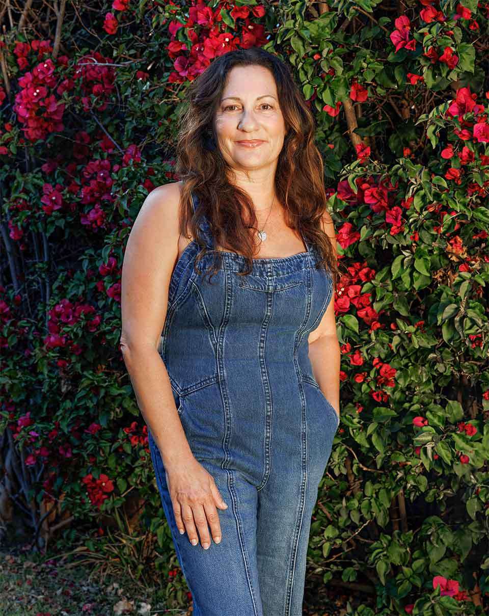 Flower Miller in jean outfit, standing in front of a red flowers.