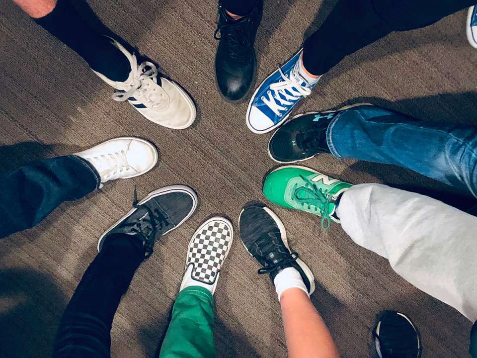 several teens putting their leg out forming a circle with their shoes