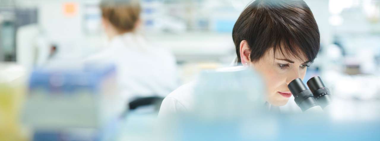 Researcher looking into a microscope