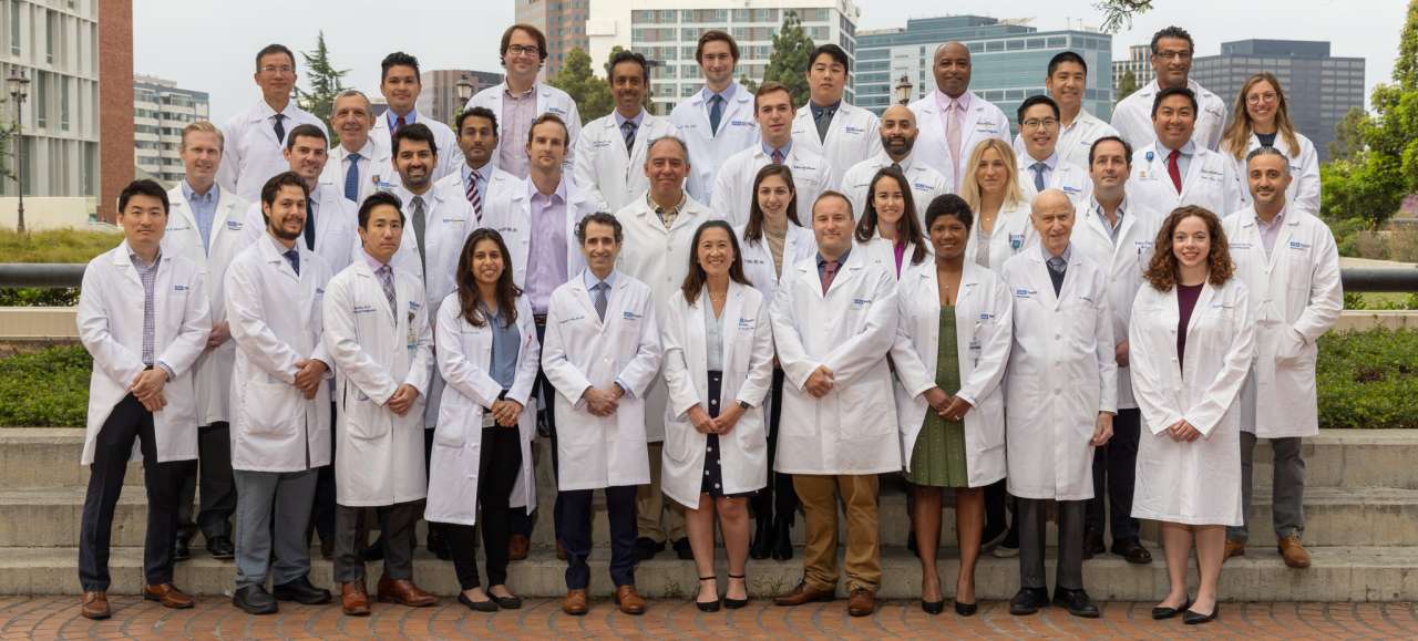 a group photo of the Neurosurgery 2023 faculty and residents in their lab coats in an outdoor setting