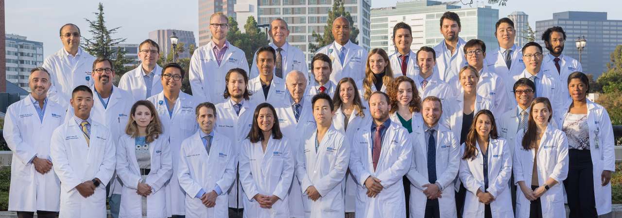 Group photograph of a diverse team of medical professionals in white coats.