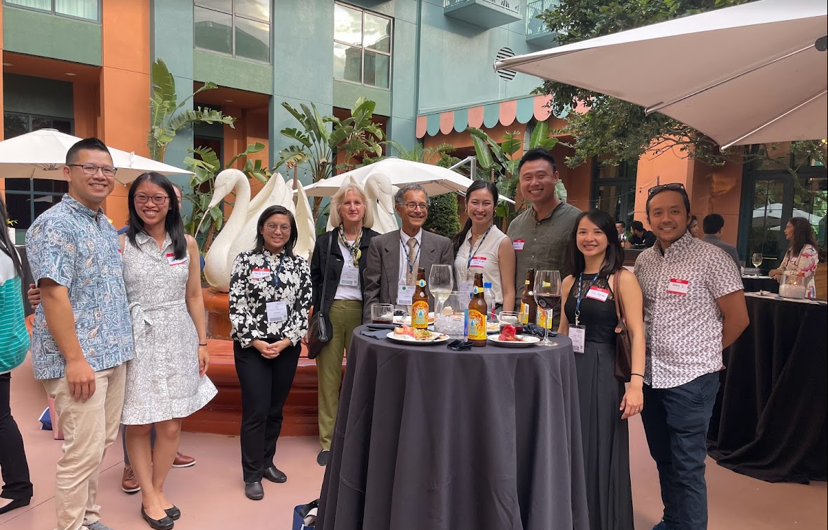  A group of physicians, pharmacists, and nurses stand around a table with drinks at the AGS Annual Scientific Meeting.