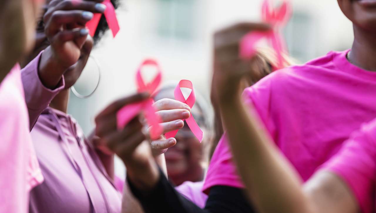 Women standing together holding breast cancer ribbons