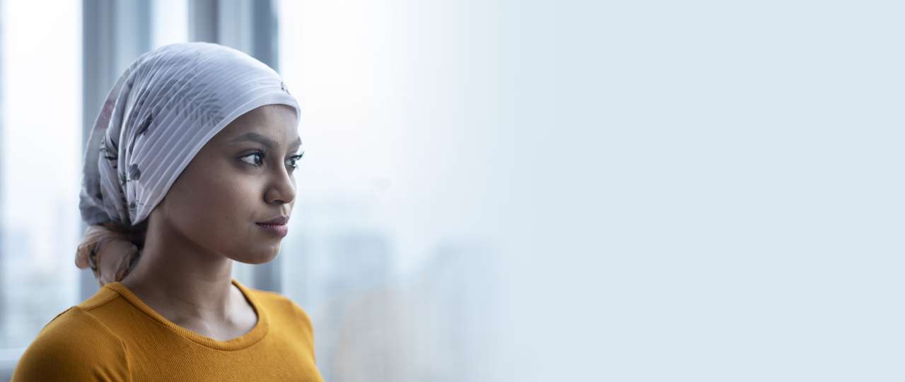 Woman wearing head scarf looking out window