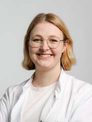 A headshot of Johanna Enke, a woman with medium length blonde hair, smiling and wearing a white lab coat.