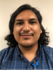 Kevin Pizarro with shoulder length black hair wearing a blue and white checkered shirt