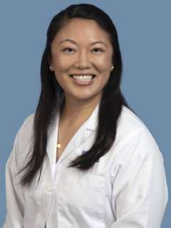 Leian Chen wearing a white lab coat, against a blue background.