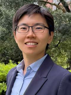 Cancer researcher Fang-Yi (Ida) Su, standing in front of a garden and looking at the camera and smiling