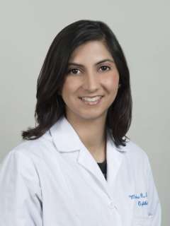Dr. Monica Khitri in a white lab coat against a neutral background.