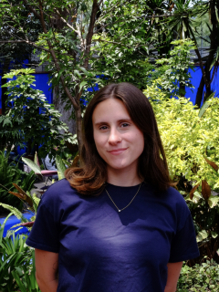 Woman in navy shirt smiling with leafy garden background