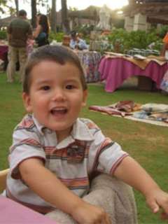 Timmy smiling seated outdoors at a gathering